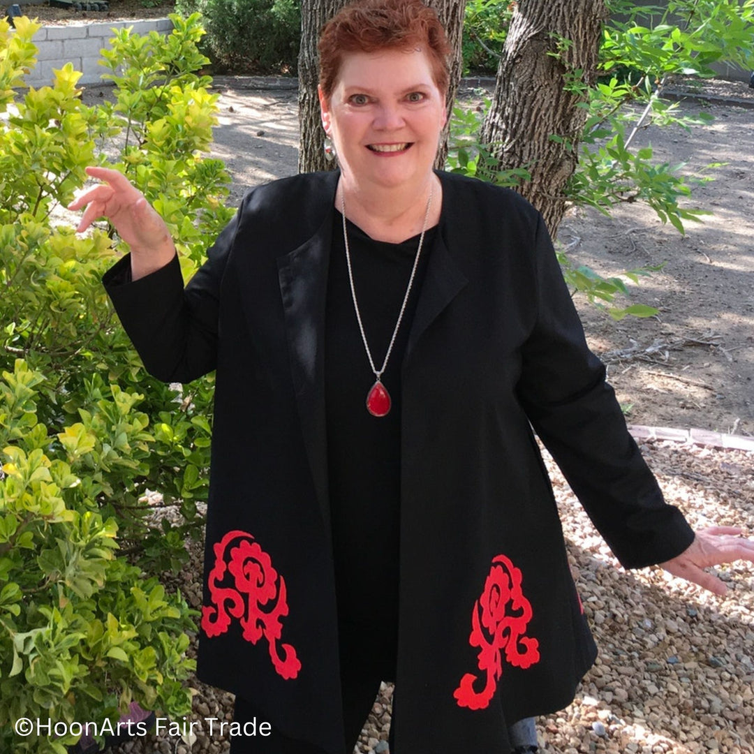 Front view of black swing jacket with large red hand-embroidered patterns, on model